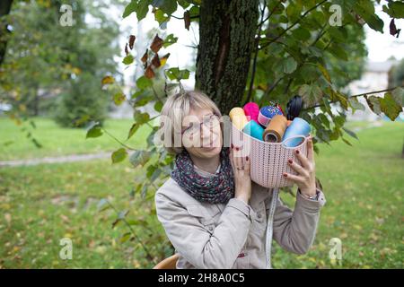 a woman seamstress holds a basket with colorful sewing threads and needles in her hands. sewing business concept Stock Photo