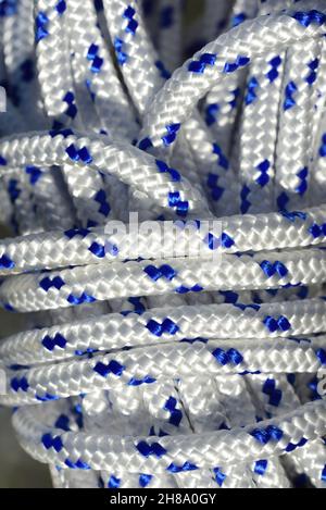 Close up and detailed view of a coiled plastic rope with white and blue fibers Stock Photo