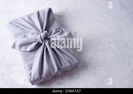 Zero waste and eco-friendly concept, gift wrapping in reusable linen fabric on white background, furoshiki present. Stock Photo