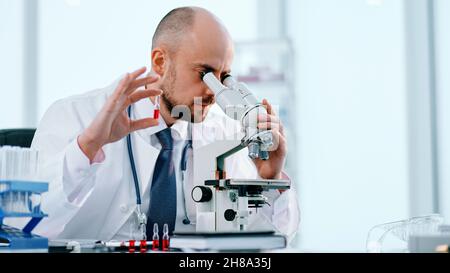 close-up. scientist studying vaccine samples through a microscope . Stock Photo