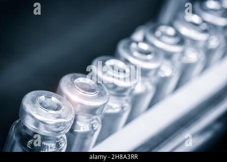 Glass bottles in production in the tray of an automatic liquid dispenser, a line for filling medicines against bacteria and viruses, antibiotics and v Stock Photo