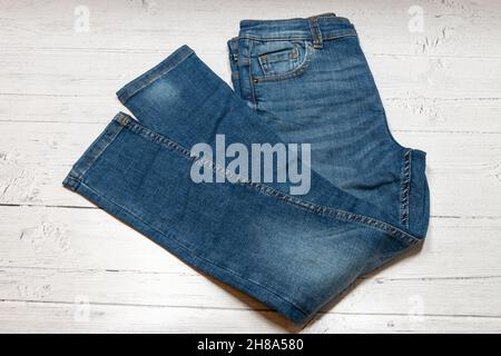 Blue Denim Jeans, Trousers laid out across a white wooden board. Stock Photo