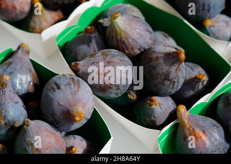 Violet figs in a paper containers are put up for sale on fruit market Stock Photo