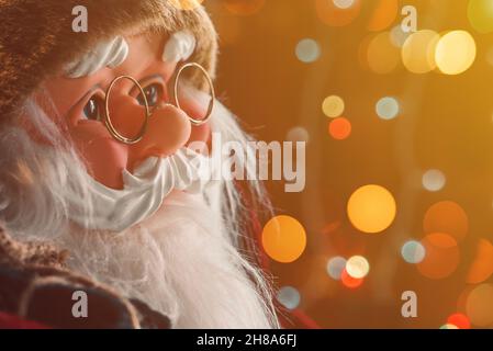 Santa Claus dummy toy with festive colorful string light bokeh background, selective focus Stock Photo