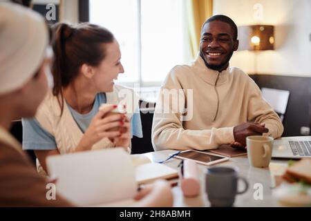 Group of students drinking coffee and laughing while working together at the table Stock Photo