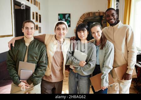 Portrait of group of students with books smiling at camera standing in the classroom of university Stock Photo