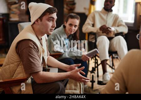 Guy talking to his teacher during a meeting in the classroom with other students Stock Photo