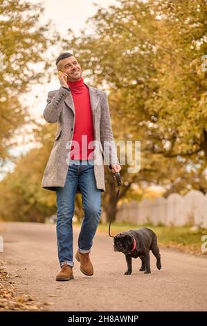 Man having a morning walk with a dog and talking on the phone Stock Photo