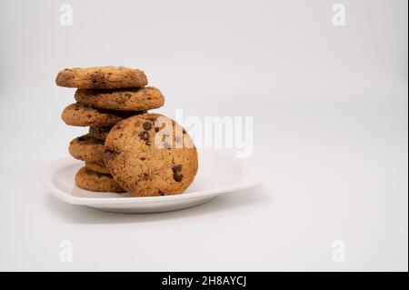 Close-up of a gingerbread cookie with chocolate leans on a stack on a white plate isolated on a white background. Stock Photo