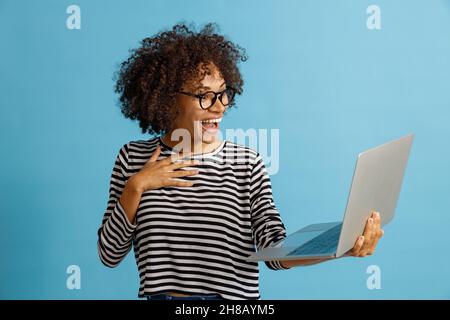 Happy young woman using notebook in studio Stock Photo