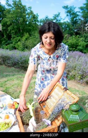 Woman arranging picnic basket in lavender field Stock Photo