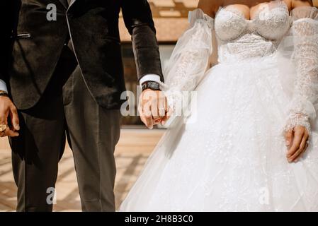 Mid section of bride and groom holding hands Stock Photo