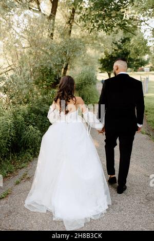 Rear view of bride and groom walking in park Stock Photo