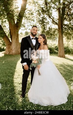 Portrait of smiling bride and groom standing in park Stock Photo