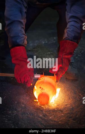 Checking diameter of a still red hot flaming crank shaft with a vernier Stock Photo