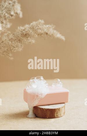 A piece of natural organic handmade soap with large foam bubbles on an abstract modern podium. Stock Photo