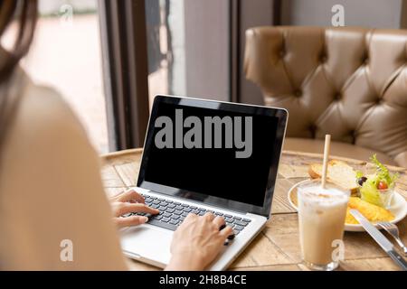 Woman's hand using and touching on laptop with blank  desktop screen in coffee shop Stock Photo