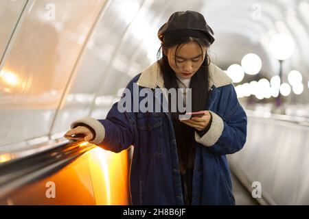 Girl can't live without smartphone. Addicted from social media korean female hold phone on escalator Stock Photo