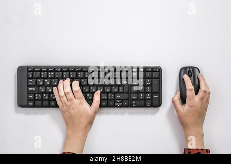 Female hands use the keyboard and mouse on a white background. Stock Photo