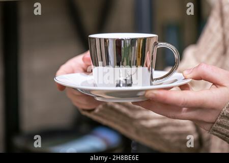 Close-up of a shiny cup with a deer in female hands. Stock Photo