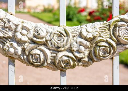 Decorative element of vintage forged white fence with garlands of flowers. Details, structure and ornaments of forged iron gate. Floral decorative orn Stock Photo