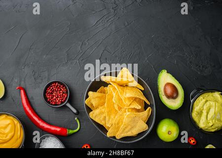 Mexican nachos chips with cheese and guacamole sauces, on black background, top view or flat lay with copy space for text Stock Photo