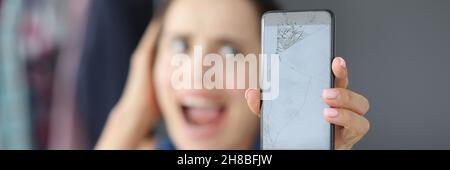 Upset woman holding broken smartphone in hands Stock Photo