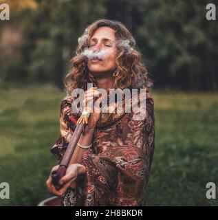 beautiful shamanic woman and indian pipe in the nature. Stock Photo