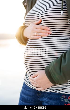 Pregnant woman hugs her belly. Close-up Stock Photo - Alamy