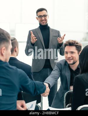 smiling employees shaking hands during a working meeting Stock Photo
