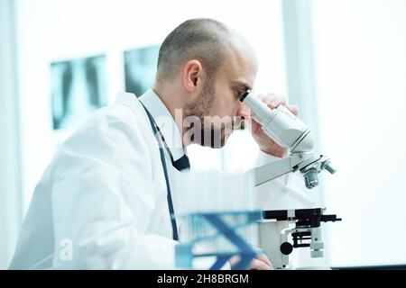 young scientist studying the obtained samples through a microscope Stock Photo