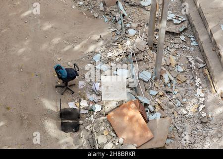 Place with pile of discarded rubbish near abandoned building at sunny day. wreckage and ruins of destroyed building in city. Stock Photo