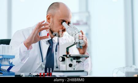 scientist studying vaccine samples through a microscope . Stock Photo