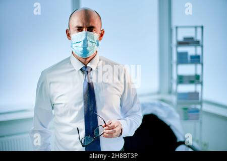 tired scientist in a protective mask standing in the laboratory. Stock Photo