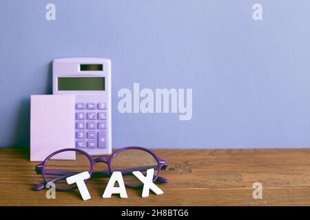 Calculator memo pad glasses on wooden desk. purple wall background. finance income tax business concept Stock Photo