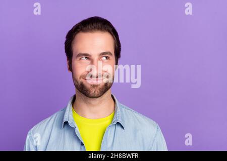 Photo of young funky smiling guy looking copyspace thinking evil plan tricky cunning isolated on violet color background Stock Photo
