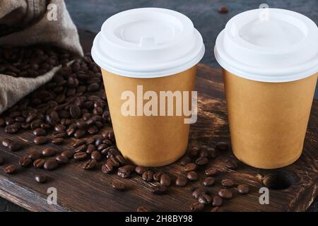 Two disposable coffee cups on table with scattered coffee beans Stock Photo