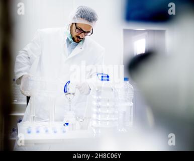 Lab technician working in a water production laboratory. Adding required components. Stock Photo