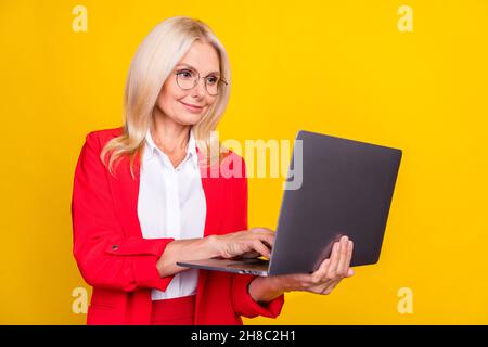 Profile side photo of senior woman type chat laptop marketer agent isolated over yellow color background Stock Photo
