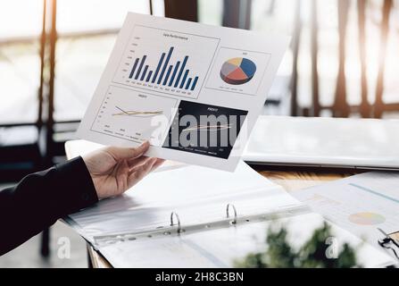 Businesswoman holding a sale performance paper to analyze sales profits. Stock Photo