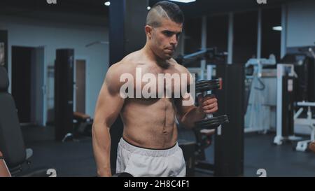 Muscular arab man training with dumbbells in the gym. Stock Photo