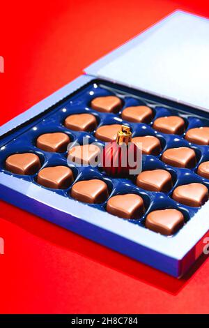 Creative Christmas concept with Christmas ball in box of heart shaped chocolates. Stock Photo
