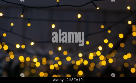 Blurred multicolored lights of a garland and branches of a Christmas tree in the foreground.Christmas and New Year background.Selective focus,copy spa Stock Photo