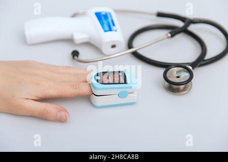 Stethoscope, pulse oximeter and thermometer gun on white background. Phonendoscope. Infrared isometric thermometer gun to check body temperature for Stock Photo