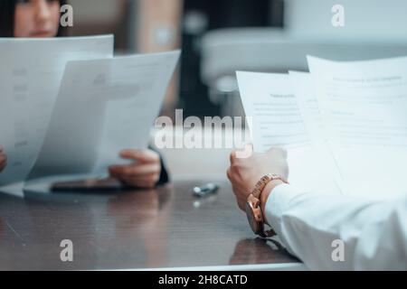 Young female manager works as a team with her client with contracts and reports in a sitting office meeting Stock Photo