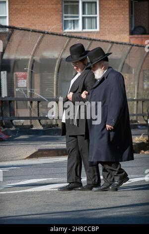 An orthodox jewish man crosses the street with help of a younger man, possibly his grandson. On an autumn day,. In Williamsburg, Brooklyn, New Yor. Stock Photo