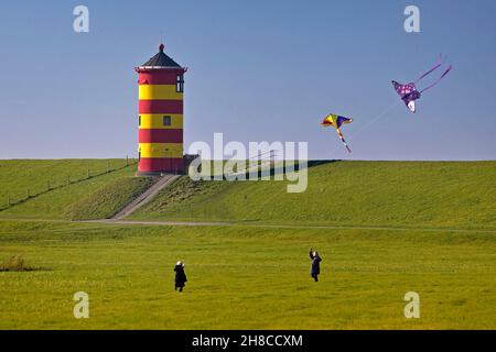 children flying a kite at lighthouse of Pilsum, Germany, Lower Saxony, East Frisia, Pilsum Stock Photo