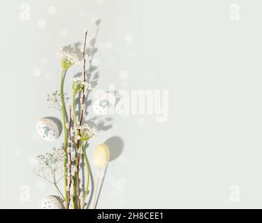 Easter background suitable for greeting card. Flower spring composition with white flowers, willow twigs and decorative eggs on a blue background with Stock Photo
