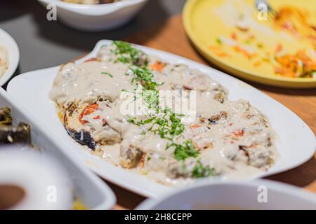 Oven-baked eggplant, and tehini sauce on top. People eat together. A table set with delicacies from the Arab cuisine. Chickpeas, salads, pitas, stuffed vegetables, meat and chicken. High quality photo. High quality photo Stock Photo