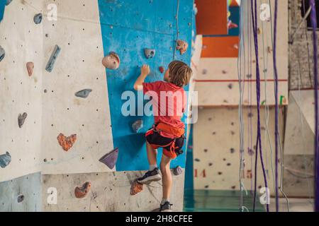 Boy at the climbing wall without a helmet, danger at the climbing wall Stock Photo